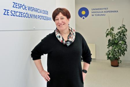 Dyrektorka dr hab. Hanna Solarczyk-Szwec, prof. UMK stojąca na tle tablicy informacyjnej