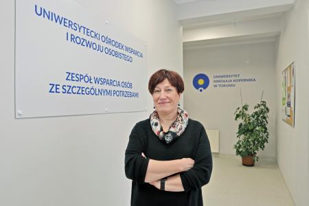 Dyrektorka dr hab. Hanna Solarczyk-Szwec, prof. UMK stojąca na tle tablicy informacyjnej